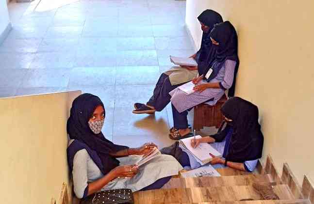 Hijab-wearing Muslim students sit on the ground in the bitter cold on the stairs, corridors and porches of the college, studying.